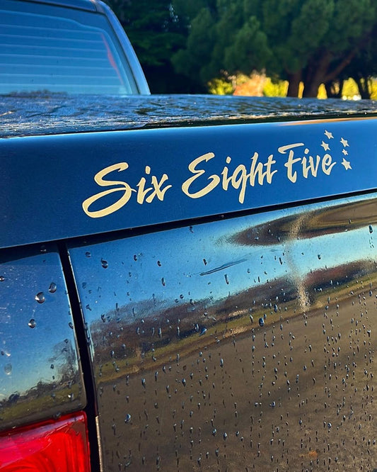 Samoan vinyl six eight five decal in gold and placed on car outdoors