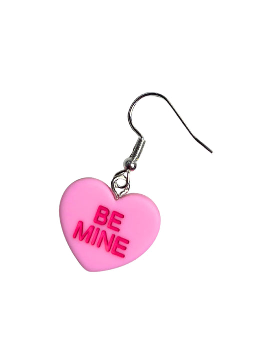 Pink heart-shaped earring with 'BE MINE' text on a white background